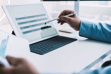 Modern çalışma ortamında istatistikleri analiz etmek için klavye ve stiklerle modern kablosuz tablet kullanan tanınmayan bir adamın tarla görüntüsü