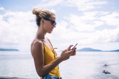 Modern akıllı telefon aygıtı ile çevrimiçi mesajlaşma sırasında mesaj göndermek için binlerce yıllık mutlu Kafkas yazma metninin yan görünümü, web rezervasyonları yapmak için hareketlilik uygulaması yükleyen genç kadın