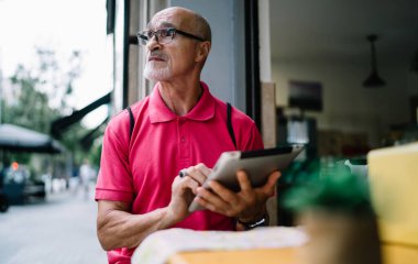 Dikkati dağılmış, pembe tişörtlü, gözlüklü, tabletli ve güneşli kafe terasındaki masada otururken gözünü kaçıran son sınıf öğrencisi.