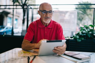 Modern dokunmatik sayfaya medya uygulaması yükleyen erkek kullanıcı boş zamanlarında masada oturuyor ve mesajlaşıyor, klasik göz giyimi konusunda Kafkas üst düzey dijital tableti güncellemek için bildirimi kontrol ediyor