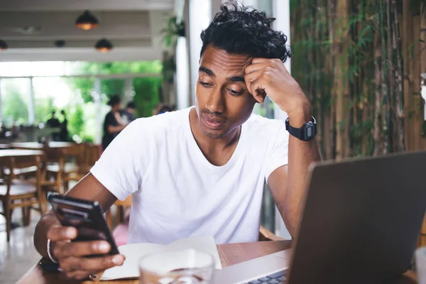 Aufmerksame Hispanische Mann Weißem Hemd Surft Smartphone Und Laptop Während — Stockfoto