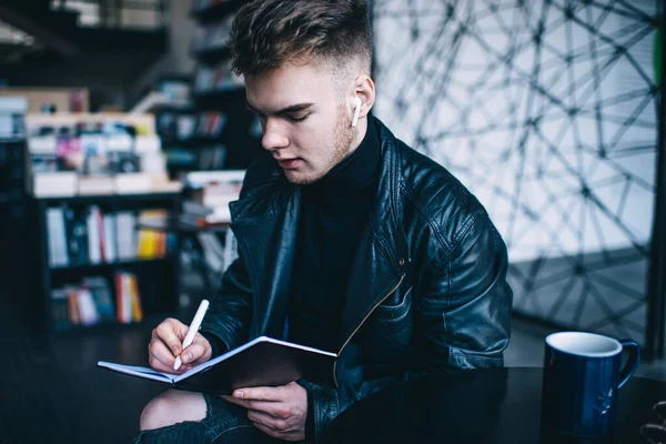 Serieuze Mannelijke Student Trendy Casual Outfit Met Draadloze Oortelefoons Schrijven — Stockfoto