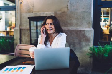 Kârlı istatistiklerle çalışan, uzaktan kumandalı kahve molasında gelen haberlere şaşıran serbest çalışan, netbook 'lu beyaz kadın, akıllı telefon uygulaması ile iletişim kuruyor.