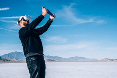 İsimsiz bir erkek, Bonneville Tuz Düzlükleri 'nde tepelerde vakit geçirirken siber uzaya dalmak için VR kulaklık takıyor.