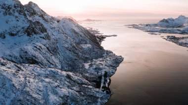Kışın karla kaplı görkemli fiyort dağlarının nefes kesici kuş bakışı görüntüsü. Hava manzaralı kaya zirveleri, resim gibi güzel doğa manzarası. Lofoten Adası İskandinav Denizi ile çevrilidir