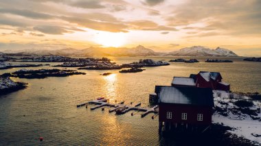 Norveç deniz suyuyla kaplı Lofoten takımadalarının nefes kesici kuş bakışı görüntüsü. Küçük balıkçı teknesinin hava görüntüsü. Altın gün batımında iskelesi olan. 