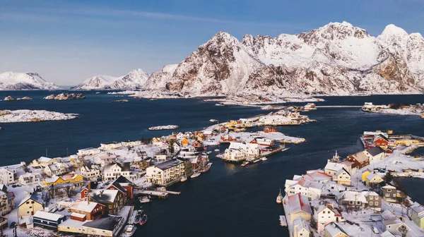 Breathtaking bird\'s eye view of Lofoten fishing village with red Traditional Norwegian houses. Aerial view from drone of panoramic island landscape with small city infrastructure between fjord