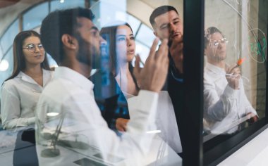 Ofisteki cam pencereyle ilgili notlar alırken, resmi olarak iş projesini tartışan farklı meslektaşların cam bakış açısıyla