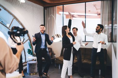 Resmi olarak ayrılan çok ırklı iş arkadaşları ofiste ayakta durup başarılarını kutlarken birbirlerine beşlik çakıyorlar.