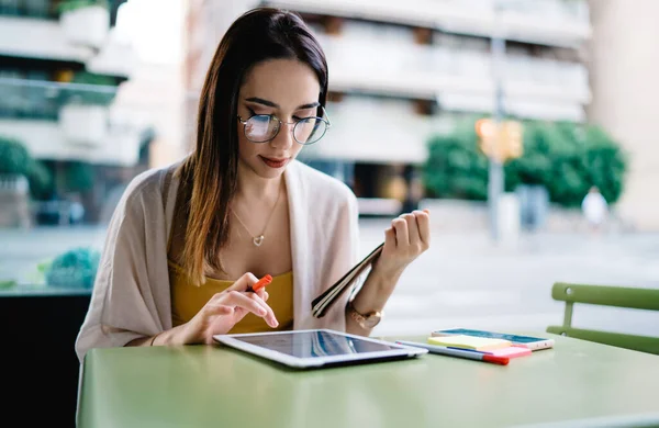 Concentrated Female Eyeglasses Summer Wear Using Tablet Checking Notes While — Stock Photo, Image