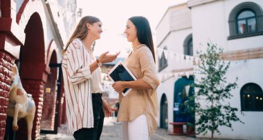 Şehir merkezinde iletişim kuran modern dokunmatik blogcu kadınlar seyahat deneyimini tartışıyor günlük kıyafetlerle gezen neşeli beyaz kadınlar sokakta boş zamanlarında sohbet ediyorlar.