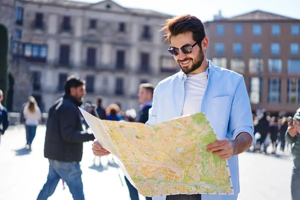 Wesoły Brodaty Podróżnik Luźnym Stroju Okularach Przeciwsłonecznych Stojący Placu Mapą — Zdjęcie stockowe