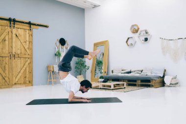 Akrep Çene 'yi çalıştıran esnek adamın yan görüntüsü böylece kalçaları ve bacakları kapalı alanda güçlendirir.