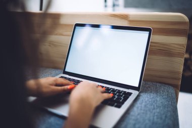 Koyu renk saçlı ve manikürlü tanınmayan bir kadın modern dizüstü bilgisayarın klavyesinde kendinden izolasyon sırasında evden uzaktayken daktilo kullanıyor.