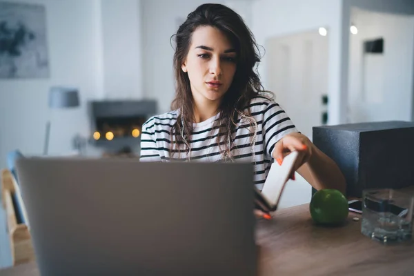 Poważne Młoda Kobieta Casual Strój Siedzi Przy Stole Przeglądania Laptopa — Zdjęcie stockowe