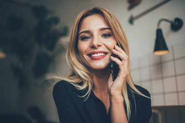 En iyi arkadaşıyla yaptığı olumlu cep telefonu konuşmasında kameraya gülümseyen neşeli kadın kullanıcının portresini kapat. Güzel beyaz kız cep telefonu uygulaması aracılığıyla telefon edip 4G iletişimi kuruyor.