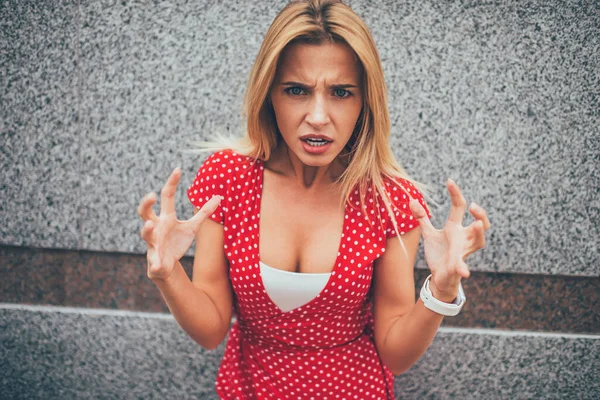 Half length portrait of angry female with expression grimace on face screaming at city urban setting, frustrated Caucasian hipster girl with raised hands feeling irate aggression and stress
