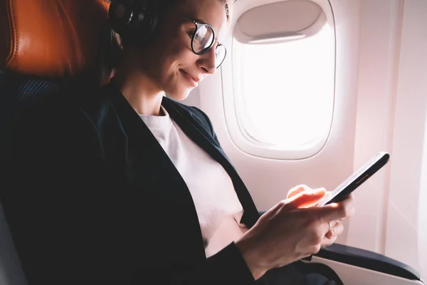 Happy sorrindo hipster menina ouvir música com celular no avião conectado a  Wi-Fi a bordo,