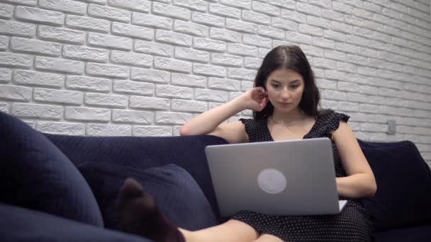Ελκυστική γυναίκα που χρησιμοποιεί φορητό υπολογιστή στον καναπέ καναπέ, χαλαρώνοντας στο σπίτι — Αρχείο Βίντεο