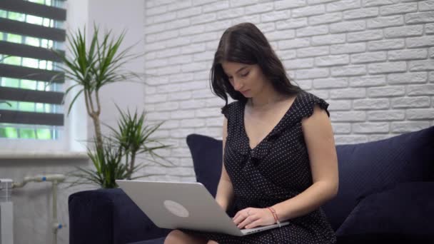 Приваблива жінка, що друкує на ноутбуці, дистанція, що працює вдома, фрілансерка — стокове відео