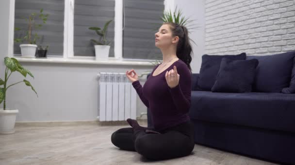 Mujer atractiva meditando en casa acogedora, pose de loto de yoga, relajante — Vídeo de stock