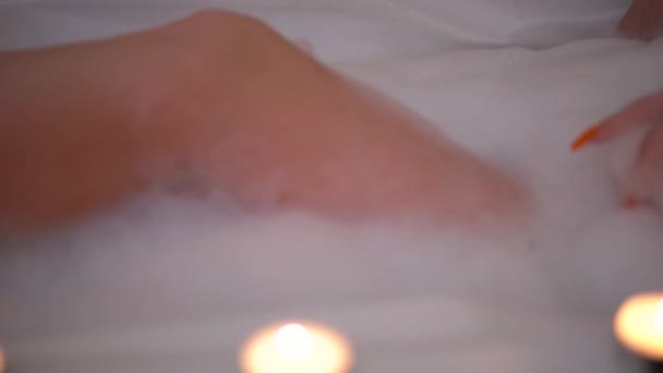 Young woman relaxing at bubble bath with candles washing bodie with foam — Stock Video