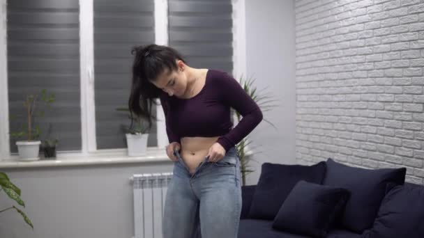 Otyła otyła kobieta ciągnąc w górę obcisłe jeansy tłuszczu talii z małe jeansy — Wideo stockowe