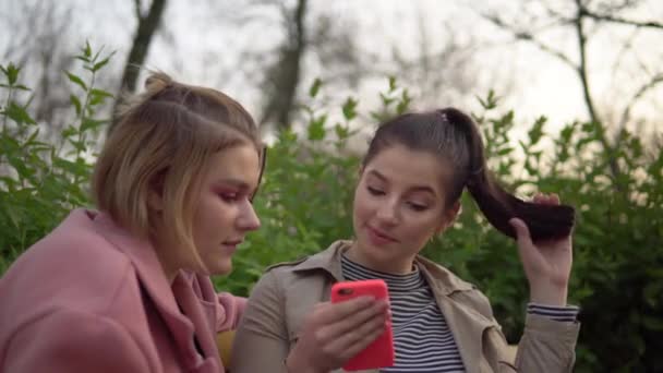 Twee aantrekkelijke gelukkige meisjes op zoek naar telefoon scherm, lachen, vriendschap concept — Stockvideo