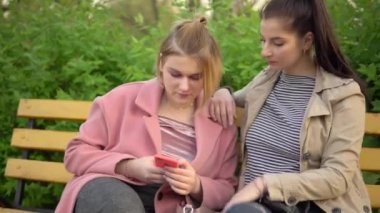 Kadın arkadaşlar parkta yürüyor, cep telefonu kullanıyor, arkadaşlık kavramı