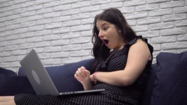 Heyecanlı kadın kazanan zaferi kutluyor, laptoptan iyi haberler okuyor.