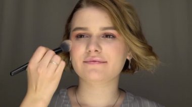 Makyaj sanatçısı model yüzüne fosforlu kalem, yakın çekim fırçası ve güzellik salonu koydu.