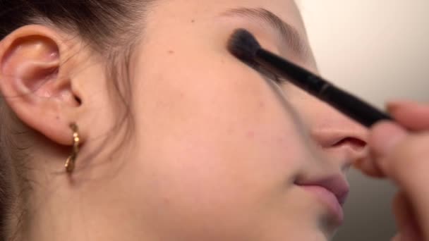 A sminkes szemhéjpúdert tett a modellre. vizuális művész munka egy szépségszalonban — Stock videók