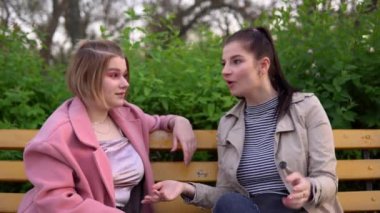 Çekici bir kadın arkadaşlarıyla duygusal konuşuyor, parkta yürüyor, mutlu kızlar.