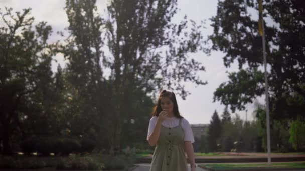 Vrouw die in het park ijs eet in de zomer — Stockvideo