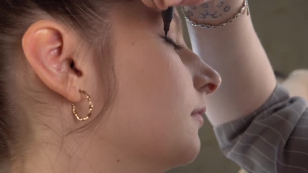 Make-up artysta robi strzałki na twarzy modelu, używać eyeliner, twarzy przemysłu kosmetycznego — Wideo stockowe
