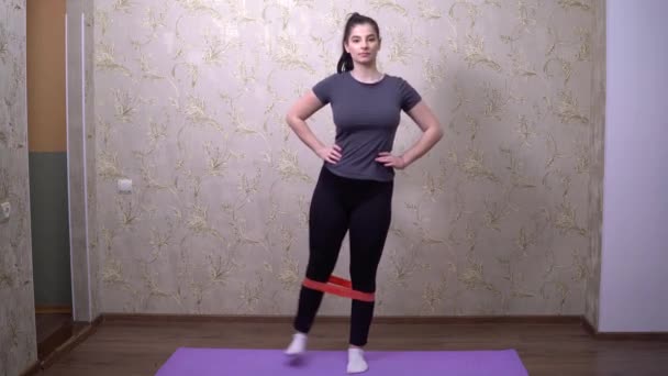 Mujer con sobrepeso haciendo deporte con goma deportiva en casa, perdiendo peso — Vídeos de Stock