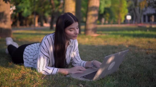 Femeie atractivă pe iarbă cu laptop, distanță de lucru online freelance — Videoclip de stoc