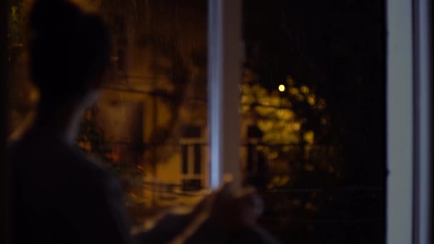 Привлекательная женщина на окне, пьет чай глядя на бурю осенью, размытие лица — стоковое видео