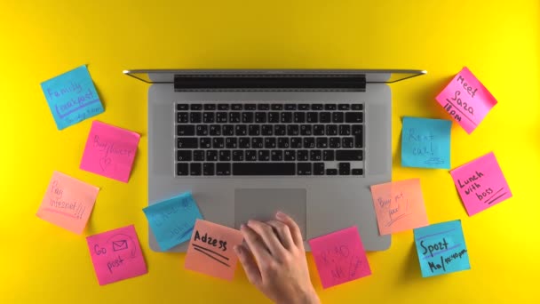 使用笔记本电脑，在工作空间上贴上文件，在贴纸、黄色桌子上做笔记 — 图库视频影像