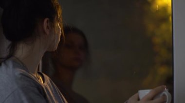 Yıldırımlar ve gök gürültüsüyle gece yağmuru, elinde bardak olan kadın.