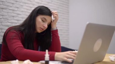 Laptopla çalışan hasta bir kadın, burnu akıyor, ofiste hasta, peçete kullanıyor.