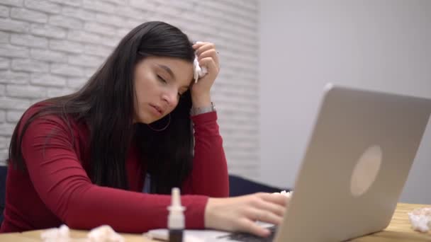 Жінка, яка працює з ноутбуком, має нежить, хвора в офісі, використовує серветку — стокове відео