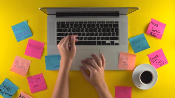 Trabajando con el ordenador portátil en el fondo amarillo, colóquelo papeles en el escritorio — Vídeos de Stock