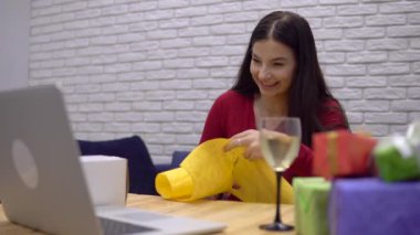 Mutlu kadın hediye paketleri hazırlıyor, hediyeler hazırlıyor, görüntülü konuşma yapıyor.