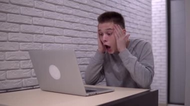 Heyecanlı mutlu adam kazandı, zaferi kutladı. Ekrana bakarak dizüstü bilgisayar kullanın.