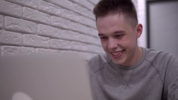 Mann schaut auf Laptop-Bildschirm und lächelt, glücklicher Mann, Freiberufler oder Student — Stockvideo
