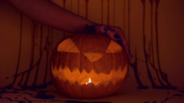 Häxa hand på glödande snidade halloween pumpa, skrämmande skräck mystisk atmosfär — Stockvideo