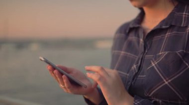 Kadın akıllı telefon kullanır, ekranı kaydırır ve dışarıda yazar, elleri kapat, blog yazarı