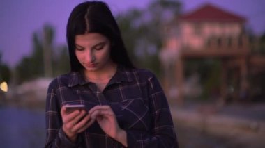 Akıllı telefon kullanan, sokakta yürüyen, cep telefonuyla mesajlaşan çekici bir kadın.