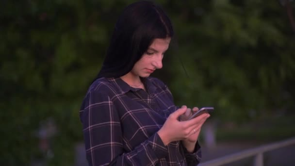 Blogger woman using smartphone texts scrolls surf internet search news on street — Vídeos de Stock